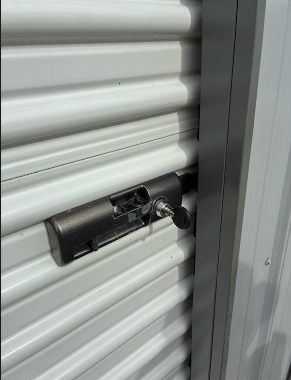 Secure lock on a white storage unit roll-up door